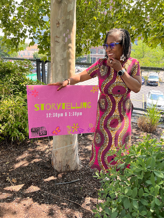 Leslie beside a storytelling sign outdoors