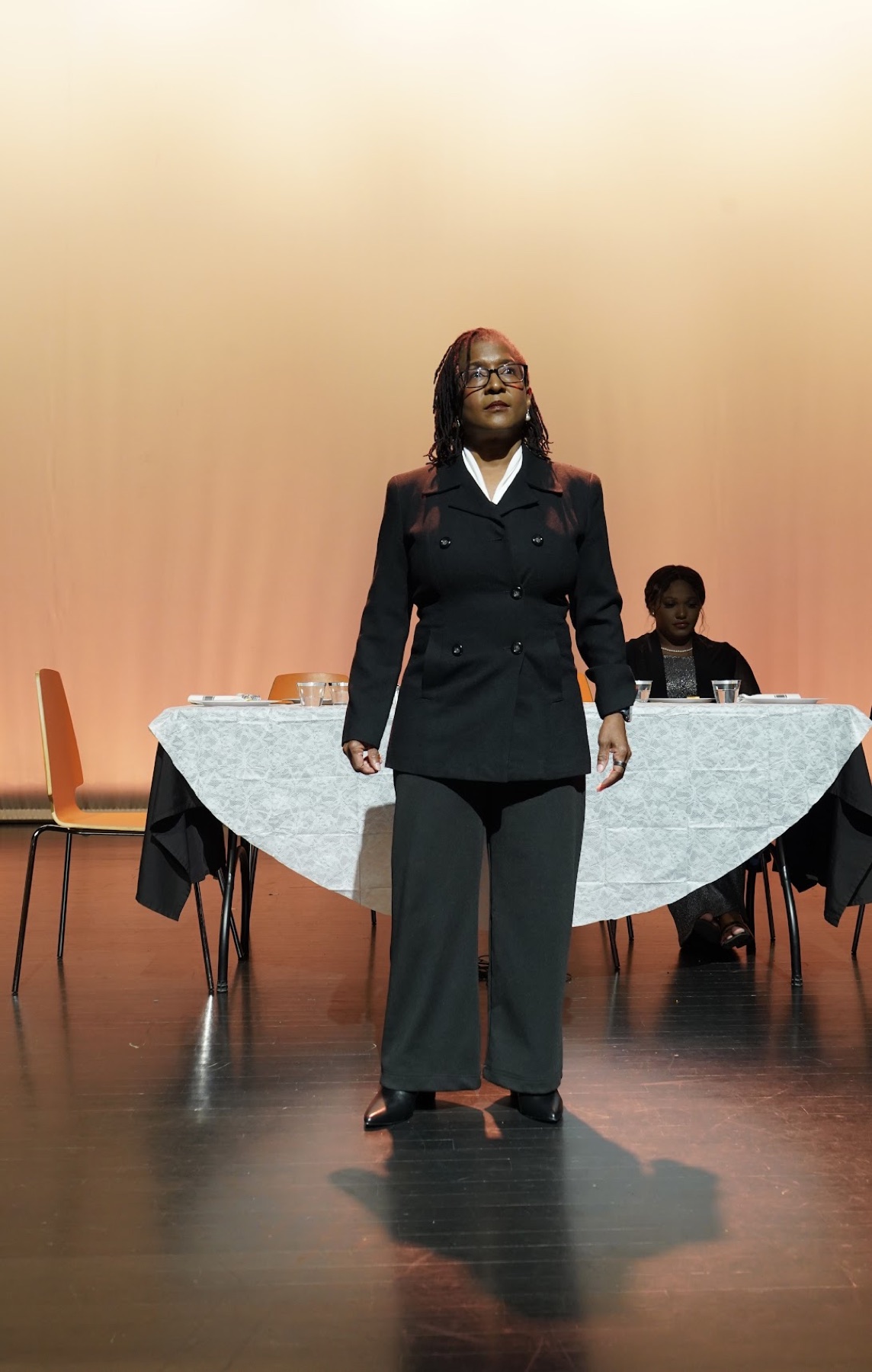 Leslie standing center stage in a black suit during When the Truth Comes Out